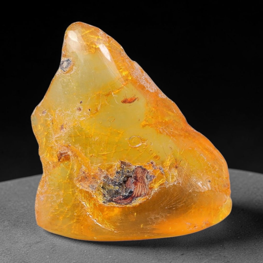12.60ct Natural Baltic Polished Loose Freeform Amber Gemstone, 39EB: This smoothly polished freeform amber piece carries warm translucent organic clarity with fine natural fossil flecks and tiny mineral inclusions suspended throughout its 27x24mm flowing unstructured s