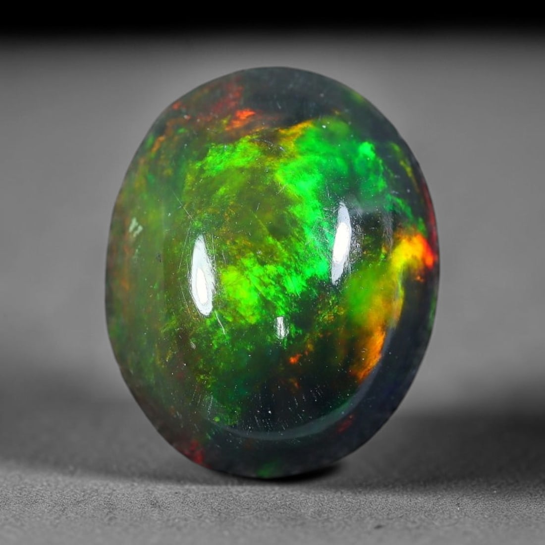 2.98ct Natural Ethiopian Welo Black Smoked Opal Cabochon Loose Gemstone, 42FX: This fully polished Ethiopian Welo opal features a dark smoked base with vivid, sweeping play-of-color shifting across its glossy dome surface, measured at 11x9x5mm. The black smoke treatment deepens 