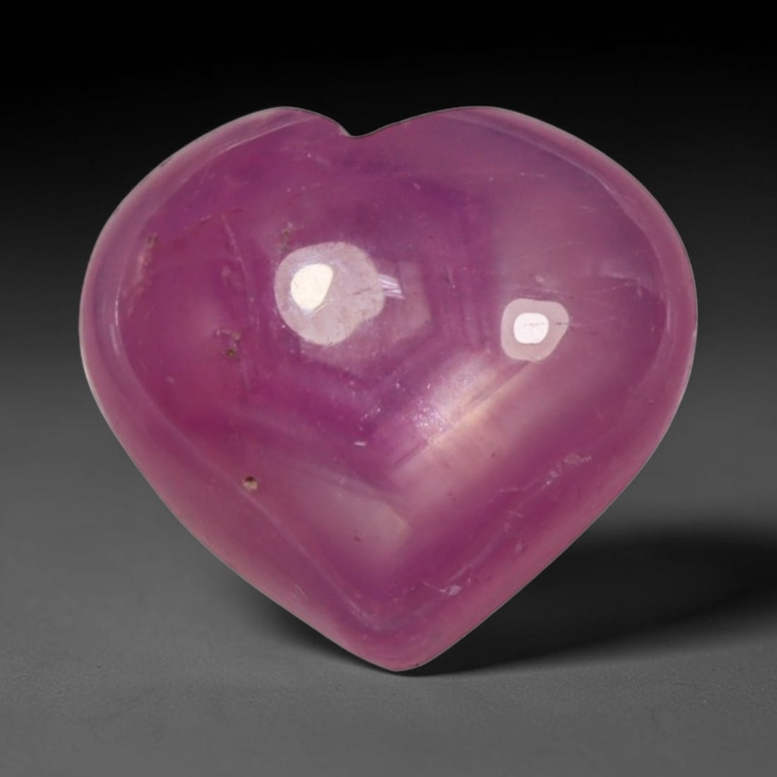 4.11ct Natural Mozambique Hot Pink Ruby Loose Gemstone, 69BP: This heart shaped Mozambique ruby cabochon measures 10.5x9.5x4.1mm, showcasing a vivid saturated hot pink body paired with stunning natural hexagonal crystal growth banding that forms a distinct geome