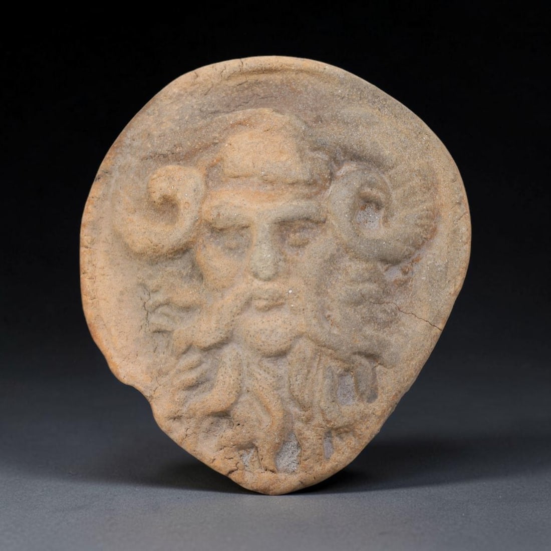 Ancient Hellenistic Terracotta Cameo Stamp (323-31 BCE), 39EK: This mould-formed terracotta cameo stamp originates within the Hellenistic cultural sphere, created as a votive and seal-function artifact bearing high-relief imagery of a horned bearded divinity, cha