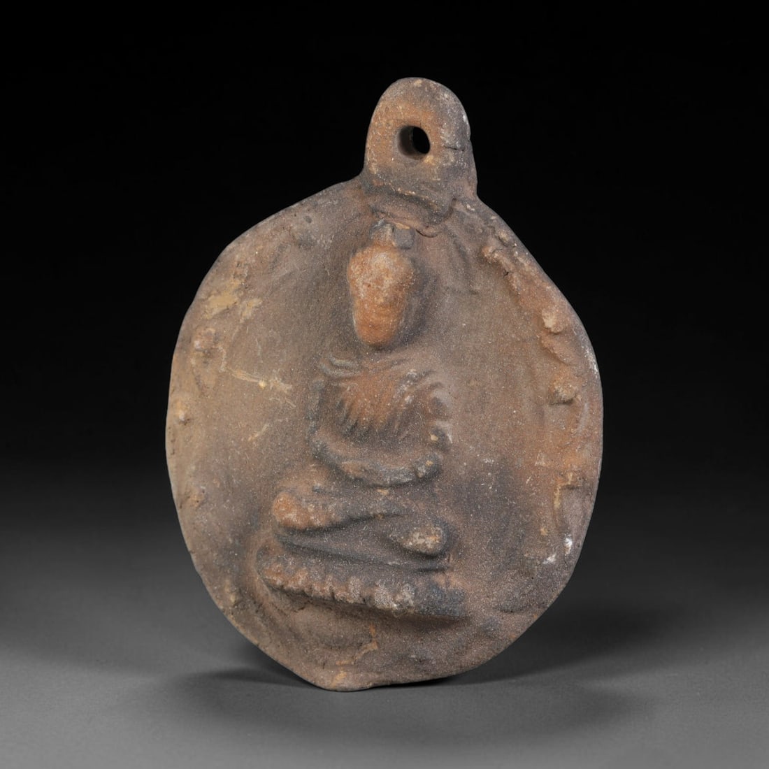 Ancient Gandhara Terracotta Buddhist Plaque (100 BCE-400 CE), 42EK: This ancient terracotta pendant plaque originates from Gandhara, a major centre of early Buddhist art along the Silk Road, shaped as a wearable devotional amulet with an integral suspension hole. The 