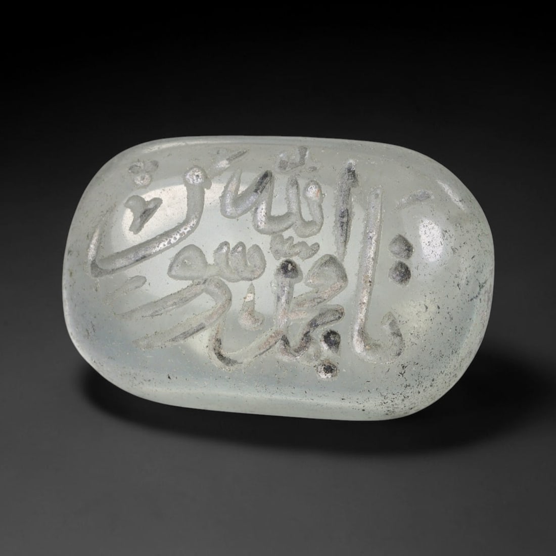 Early Vintage Islamic White Glass Calligraphic Intaglio Seal Cabochon (Post 1900 CE), 89BX: This early vintage glass intaglio seal cabochon draws from enduring Islamic seal-making traditions, formed from translucent pale glass with a smoothly rounded polished surface. The face features caref