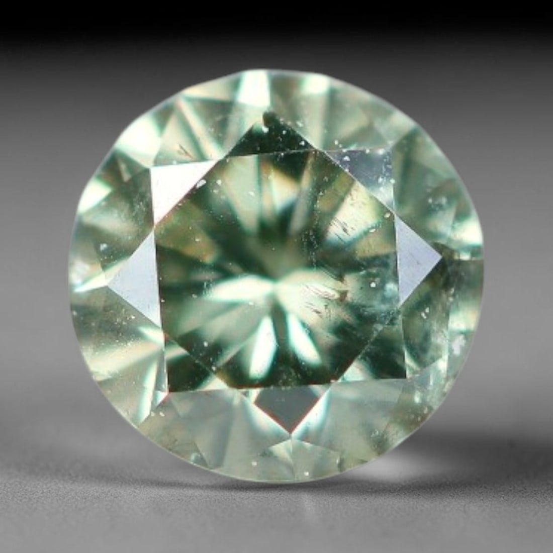 0.11ct Round Natural Fancy Green Diamond Loose Gemstone, 97BE: This polished natural round fancy diamond displays soft mint-green colouration, with fine microscopic native mineral specks scattered within its crystal interior, measured at calibrated dimensions of 