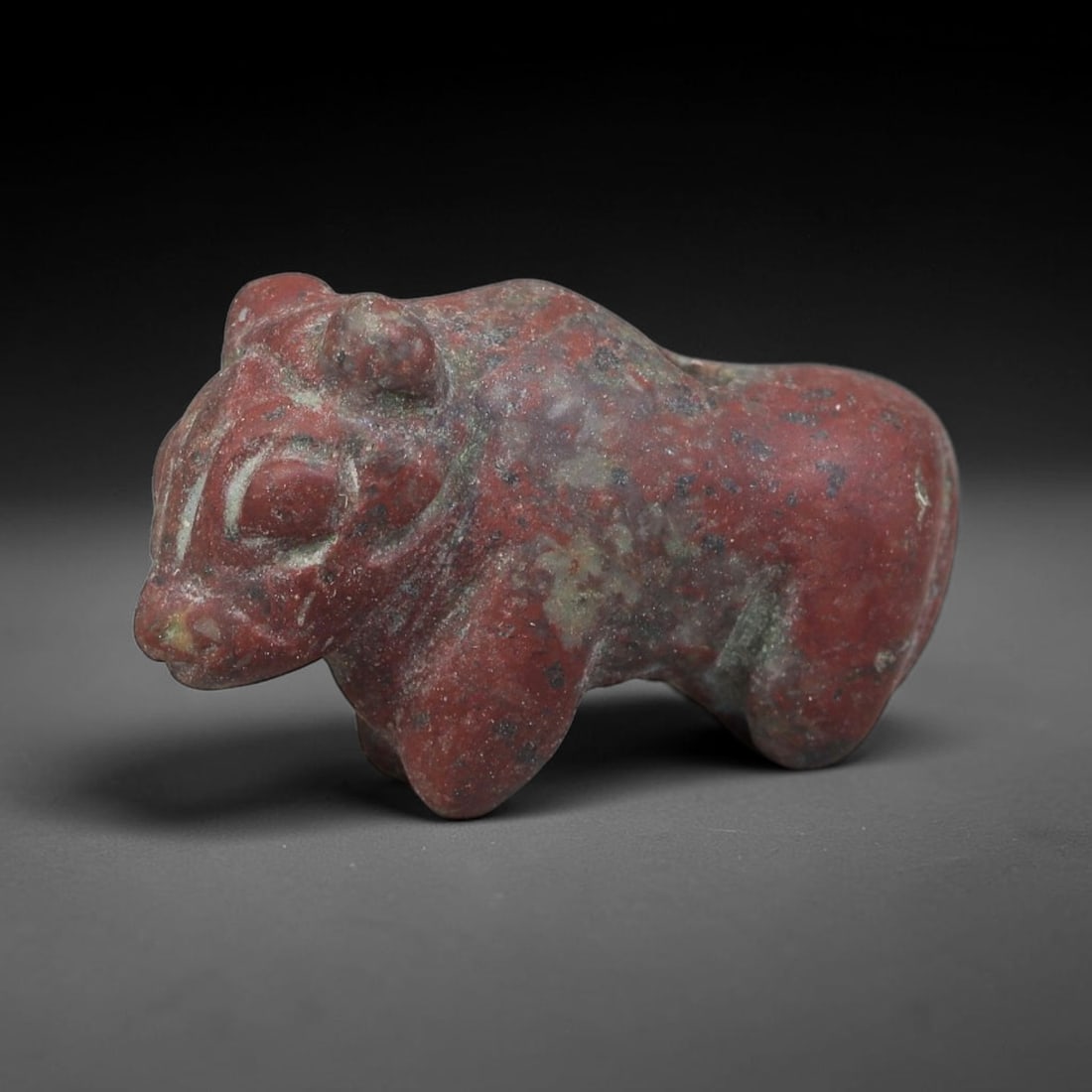 Ancient Sumerian Civilization Red Speckled Hardstone Bovid Amulet (4500-2000 BCE), 8EC: This carved red speckled hardstone bovid amulet originates from Ancient Sumerian Civilization of southern Mesopotamia, where bovine zoomorphic talismans represented strength, agricultural abundance an