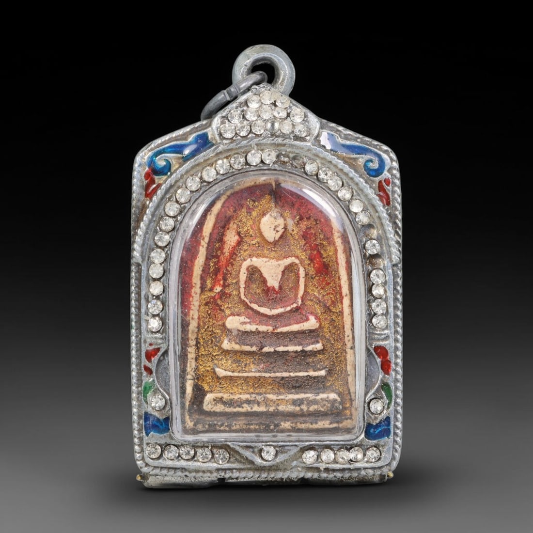 Thai Buddhist Folk Tradition Enclosed Amulet Pendant with Decorative Metal Casing, 45AH: This Thai sacred amulet is housed within an ornate hinged metal protective casing fitted with a top loop for wear as a pendant. The casing features intricate embossed surface detailing and a continuou