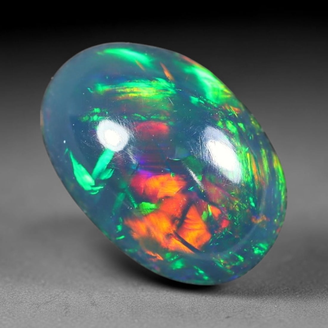 1.50ct Natural Ethiopian Welo Black Smoked Opal Cabochon Loose Gemstone, 29FX: This fully polished Ethiopian Welo opal features a dark smoked base with vivid, sweeping play-of-color shifting across its glossy dome surface, measured at 10x7x4mm. The black smoke treatment deepens 