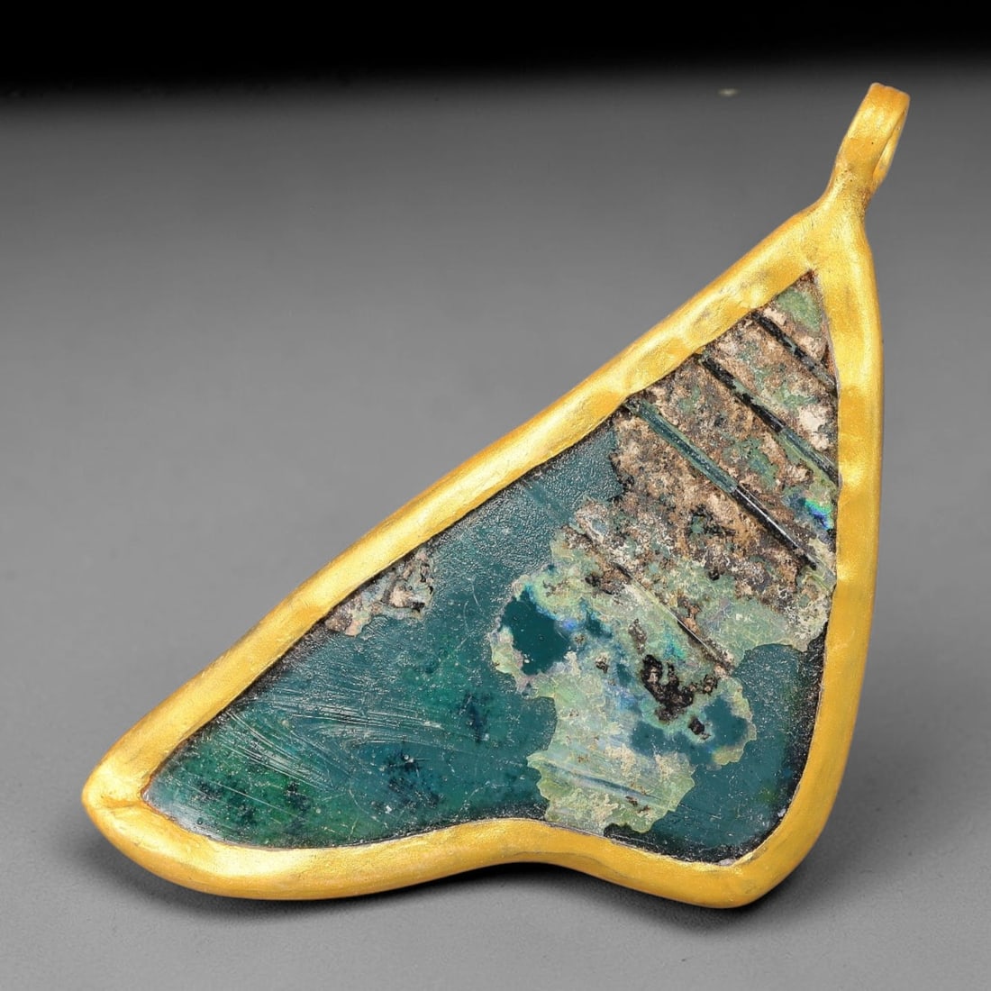 Ancient Roman Glass Slag in Modern Gilt-Edge Pendant, 51FY: This contemporary pendant is crafted from ancient Roman glass slag, featuring a fragmented, iridescent glass surface with weathered patina. The irregular form is bordered by a subtle gilt frame, added