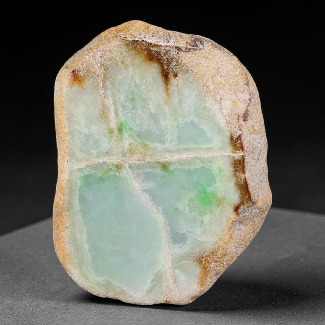 455ct Natural Type A Burmese Yellow Skin Floating Green Spot Jadeite Jade Sliced Rough, 16FA: This specimen is a natural sliced rough pebble of untreated Type A Burmese jadeite, fully retaining weathered yellow-brown outer rind along its entire perimeter edge. Its polished cut face presents se