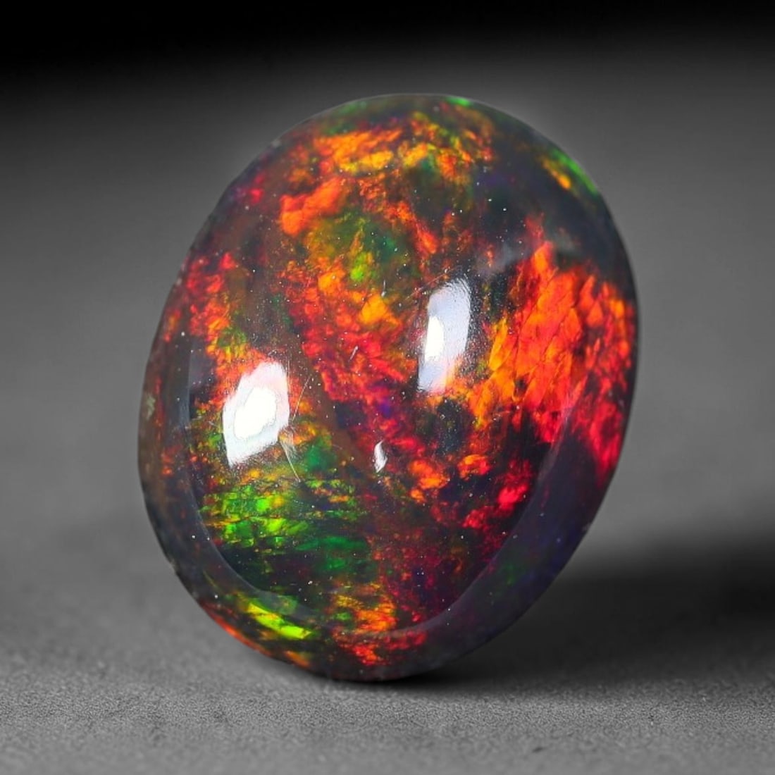 1.93ct Natural Ethiopian Welo Black Smoked Opal Cabochon Loose Gemstone, 67FX: This fully polished Ethiopian Welo opal features a dark smoked base with vivid, sweeping play-of-color shifting across its glossy dome surface, measured at 10x8x4mm. The black smoke treatment deepens 