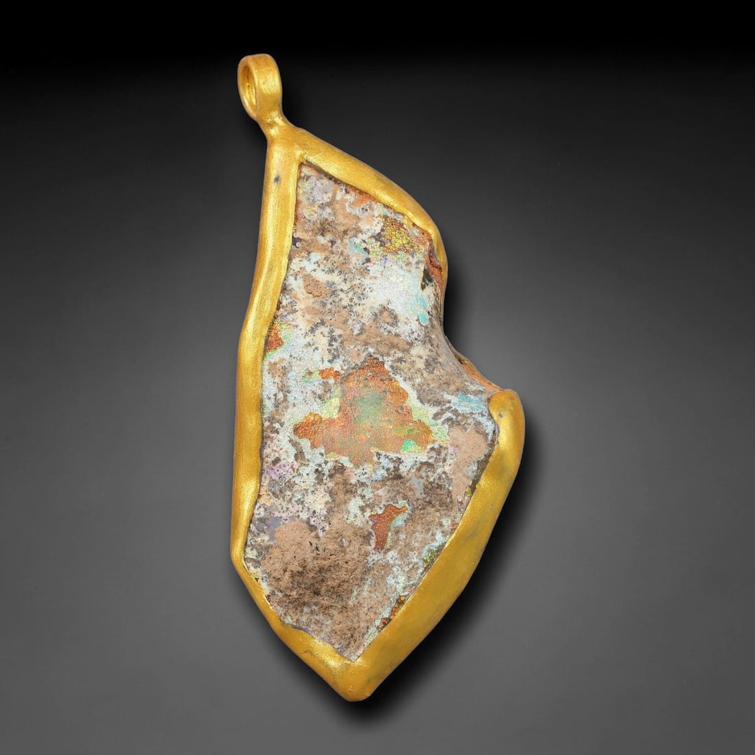 Ancient Roman Glass Slag in Modern Gilt-Edge Pendant, 73FY: This contemporary pendant is crafted from ancient Roman glass slag, featuring a fragmented, iridescent glass surface with weathered patina. The irregular form is bordered by a subtle gilt frame, added