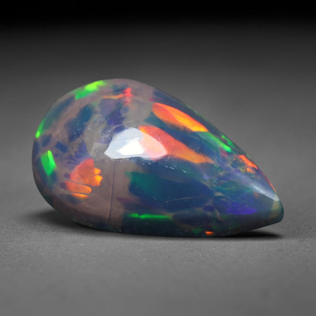 2.21ct Natural Ethiopian Welo Black Smoked Opal Cabochon Loose Gemstone, 64BY: This fully polished Ethiopian Welo opal features a dark smoked base with vivid, sweeping play-of-color shifting across its glossy dome surface, measured at 13x8x5mm. The black smoke treatment deepens 