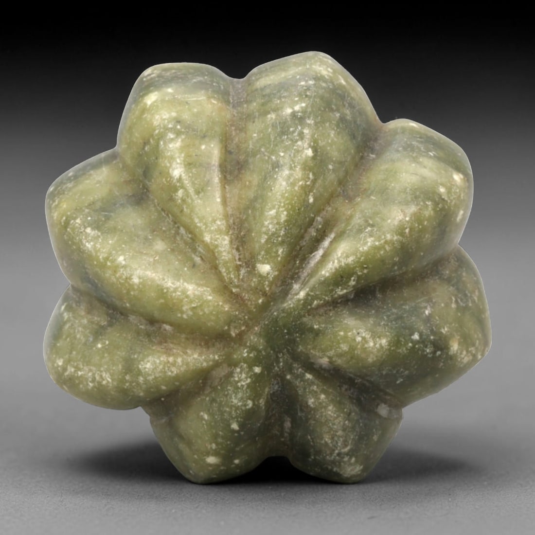 A Chinese Hetian Jade Melon-Shaped Bead, 20th Century, 96FH: Carved from greenish Hetian jade with lighter and darker tonal variations and scattered natural inclusions, the object is modeled in the form of a melon with a rounded, lobed body. The surface is arti