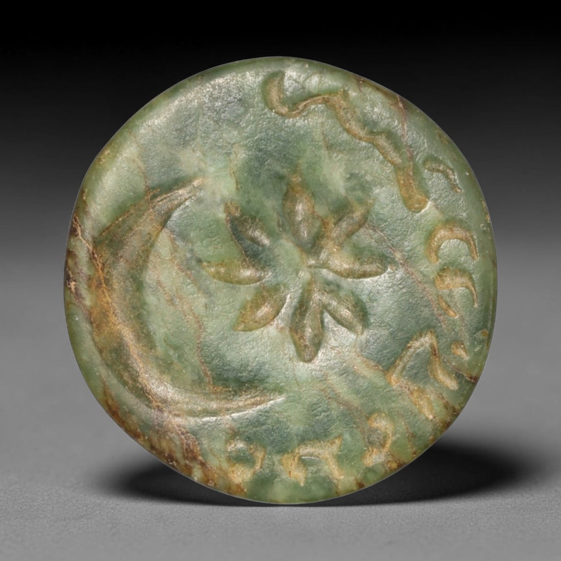 Ancient Sasanian Persian Variegated Green Stone Conoid Stamp Seal (c.224-651 CE), 22ED: This marbled green conoid stamp seal originates from Ancient Sasanian Persian culture. The circular sealing face bears an incised floral motif paired with crescent symbols and peripheral script markin
