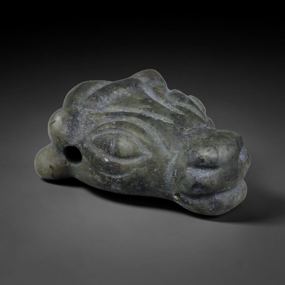 Ancient Sasanian Persian Empire Dark Green Stone Bovid Head Amulet (224-651 CE), 30EC: This carved dark green mottled stone bovid head amulet originates from the Sasanian Persian Empire, where bovine-headed talismans represented strength, fertility and sacred protection in Zoroastrian t