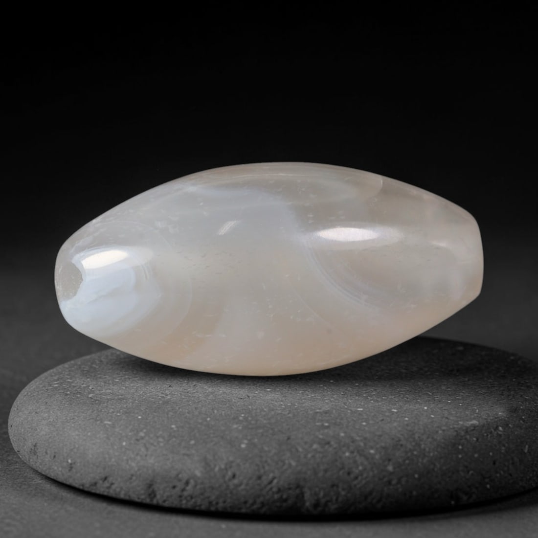 Ancient Yuan Dynasty Subtle Pale Cream Banded Agate Oval Barrel Bead (1271-1368 CE), 71AD: This softly translucent banded agate barrel bead originates from China's Yuan Dynasty, a period blending Han lapidary traditions with Central Asian ornamental influences fostered by expansive cross-co