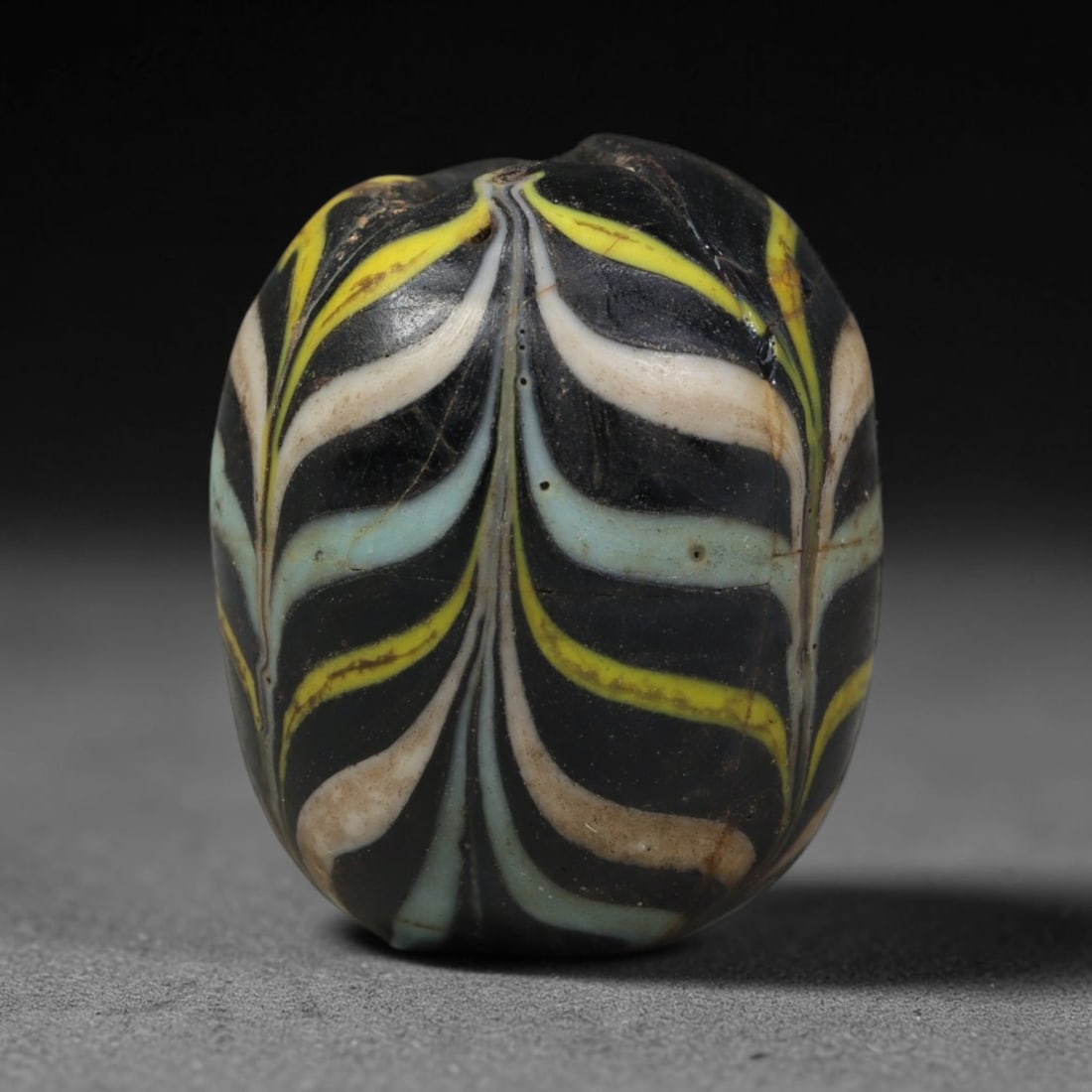 Ancient Islamic Hand Crafted Glass Bead Talisman, 32AC: Miniature antique wearable bead formed from hand-worked glass material, originating from ancient Islamic period glassmaking traditions across the Near East and North African cultural spheres. Glass wa