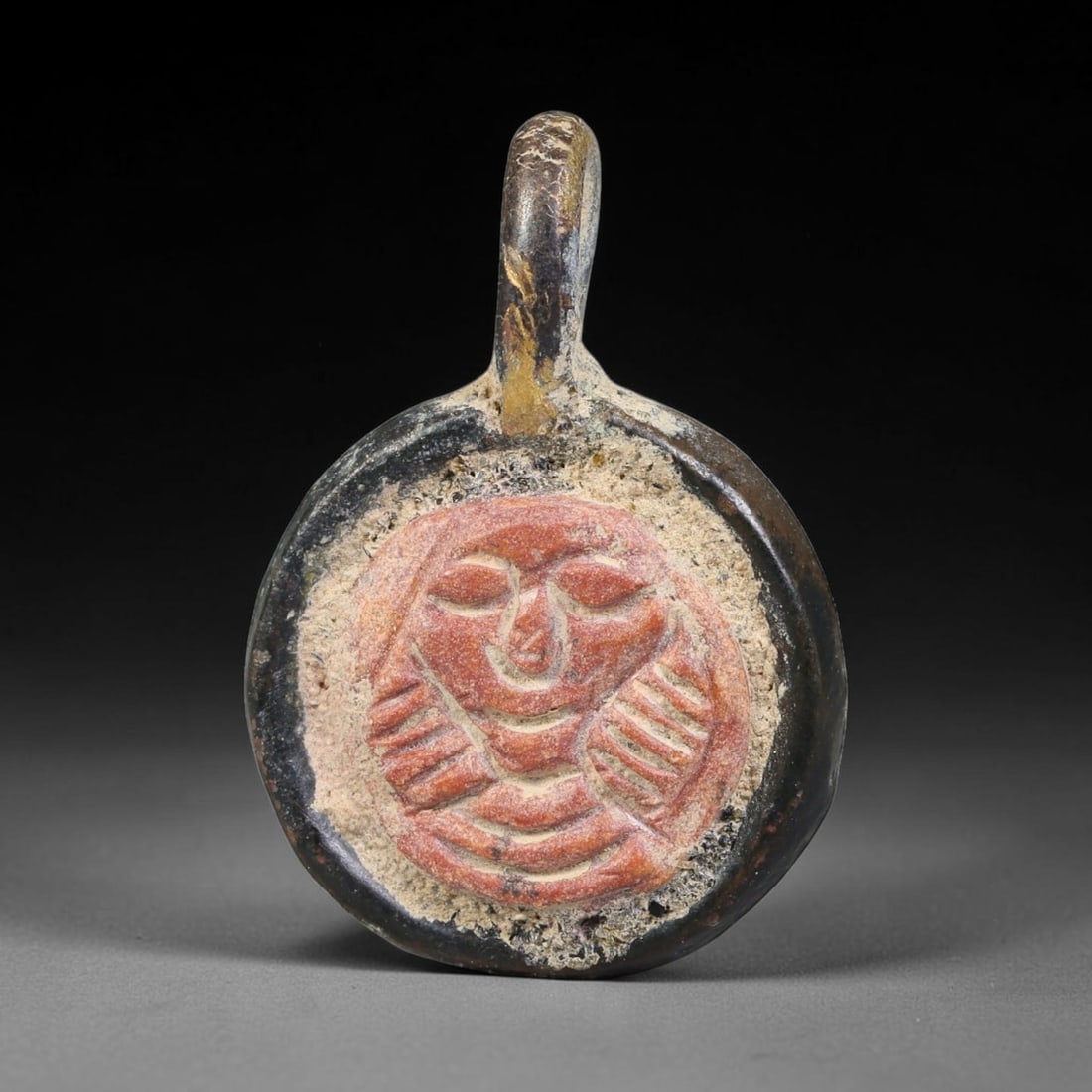 Ancient Medieval Byzantine Bronze Pendant With Stone Cameo (500-1200 CE), 71EH: This antique circular bronze pendant originates from medieval Byzantine cultural tradition, set with an inset carved stone cameo and made to serve as a wearable protective personal amulet. The bronze 