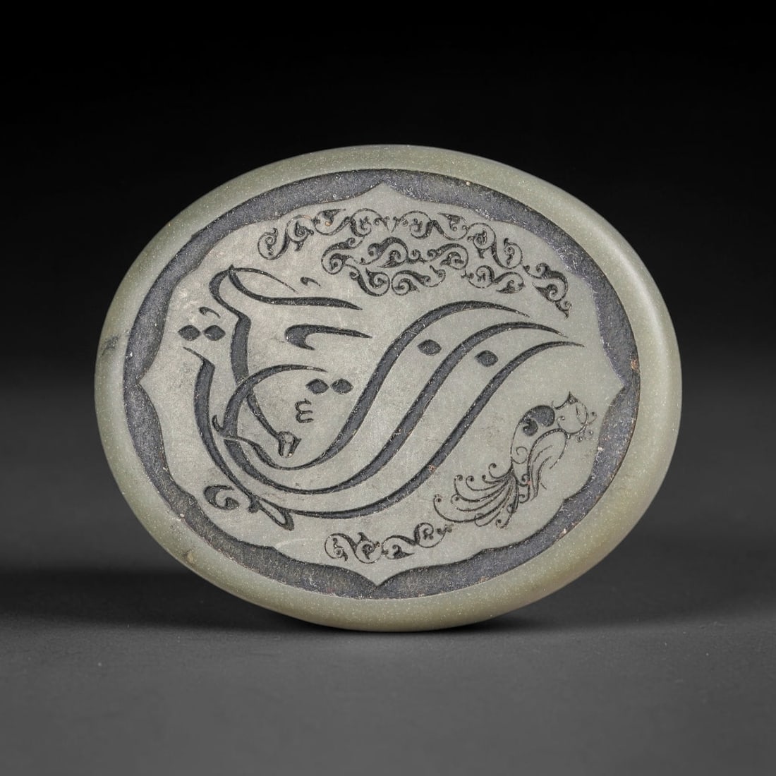 An Islamic Natural Green Stone Circular Script Engraved Talisman Tablet, 34FG: This polished green stone talisman tablet with elaborate concentric layered script engraving covering the central face, framed within a stylized petal-shaped inner border. Fine recessed engraved detai