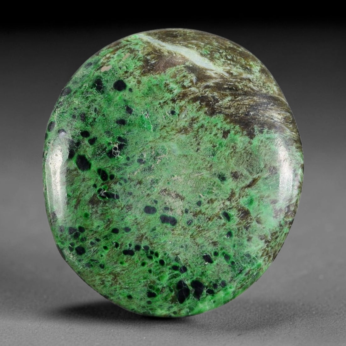 16.35ct Natural Burmese Type A Black Spot Moss Green Jadeite Jade Cabochon, 24FA: This single untreated natural Burmese Type A oval jadeite jade cabochon weighs 16.35ct with dimensions of 26.5x23.2x3mm. The bright moss green matrix is densely dotted with round black mineral inclusi