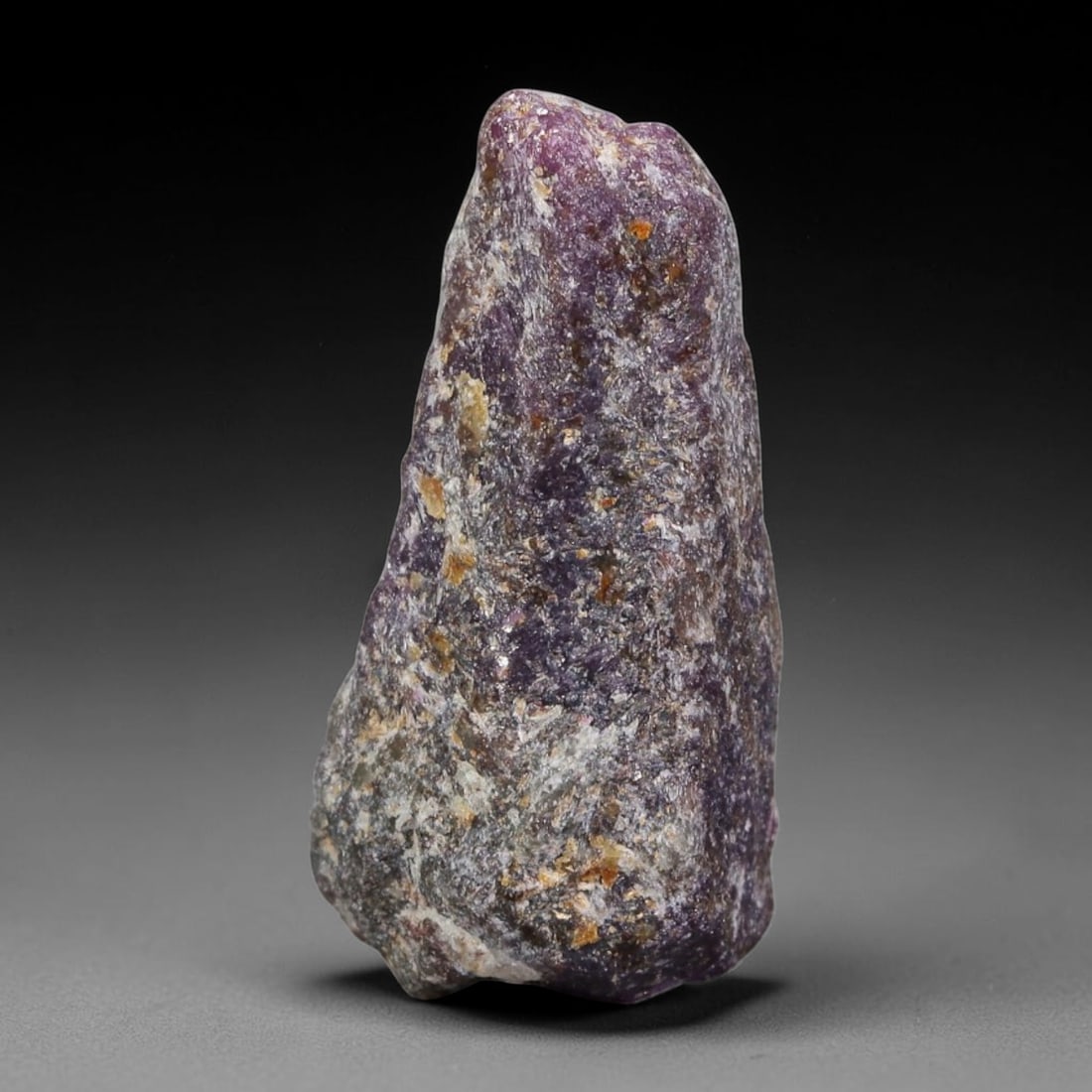 28.28ct Natural Mauritania Ruby Rough (Unheated), 61AT: Natural unheated corundum rough sourced from Mauritania gem deposits, featuring a tapered upright crystalline form blanketed by grey silicate host matrix with scattered patches of deep magenta-pink ru