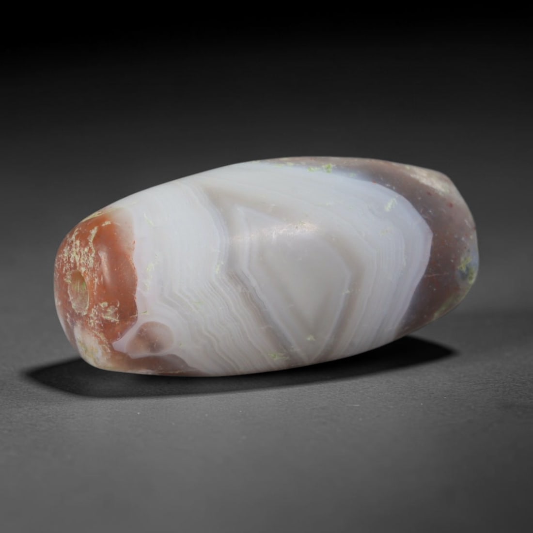 Ancient Neo-Assyrian Empire Red Terminal Geometric Banded Agate Barrel Bead (911-609 BCE), 64AD: This antique banded agate barrel bead originates from the Neo-Assyrian Empire, a dominant Iron Age Mesopotamian civilization celebrated for master lapidary production of ritual protective talismans fo