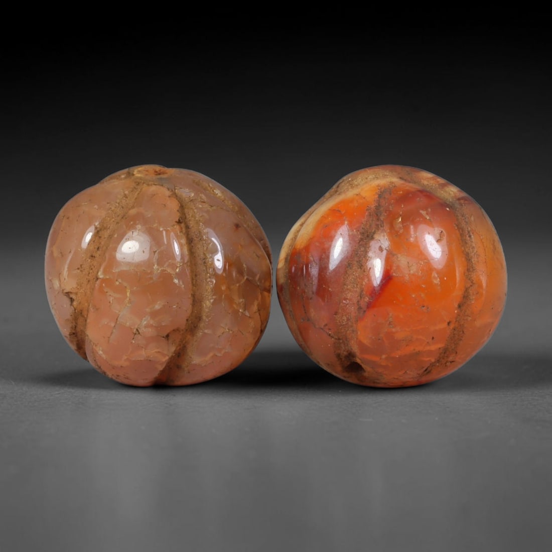 Ancient Medieval Khmer Angkor Culture Carved Carnelian Melon Bead Pair (802-1431 CE), 56AE: This matched pair of antique hand-carved melon form carnelian beads originates from Khmer Angkor Culture, the medieval Southeast Asian civilization renowned for crafting ritual chalcedony adornments f