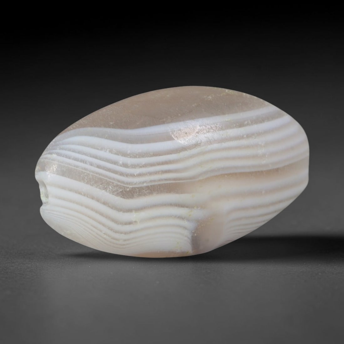 Ancient Mature Indus Valley Wavy Parallel Banded Agate Barrel Bead (2600-1900 BCE), 100AD: This antique banded agate barrel bead originates from the Mature Indus Valley Civilization, one of the world's earliest planned urban cultures renowned for standardized mass production of agate beads 