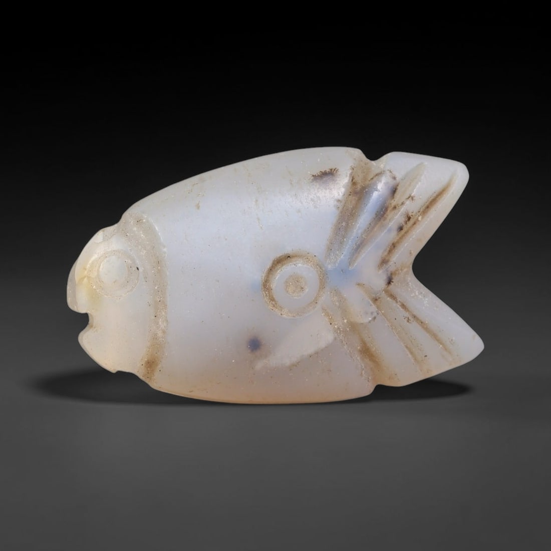 Ancient Coptic Christian Egyptian Culture Chalcedony Fish Amulet Bead (300-1000 CE), 16EC: This antique fish-shaped amulet bead carved from pale chalcedony originates from Coptic Christian Egyptian culture, where the fish served as a core sacred symbol of faith and protection within early C