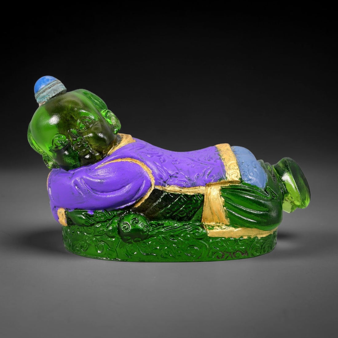 Vintage Chinese Liuli Glass Snuff Bottle - Reclining Sleeping Child, 42AS: This snuff bottle is moulded from translucent green liuli glass and shaped as a peaceful reclining sleeping child. The purple robe has embossed patterns accented with gilded trim, paired with blue and