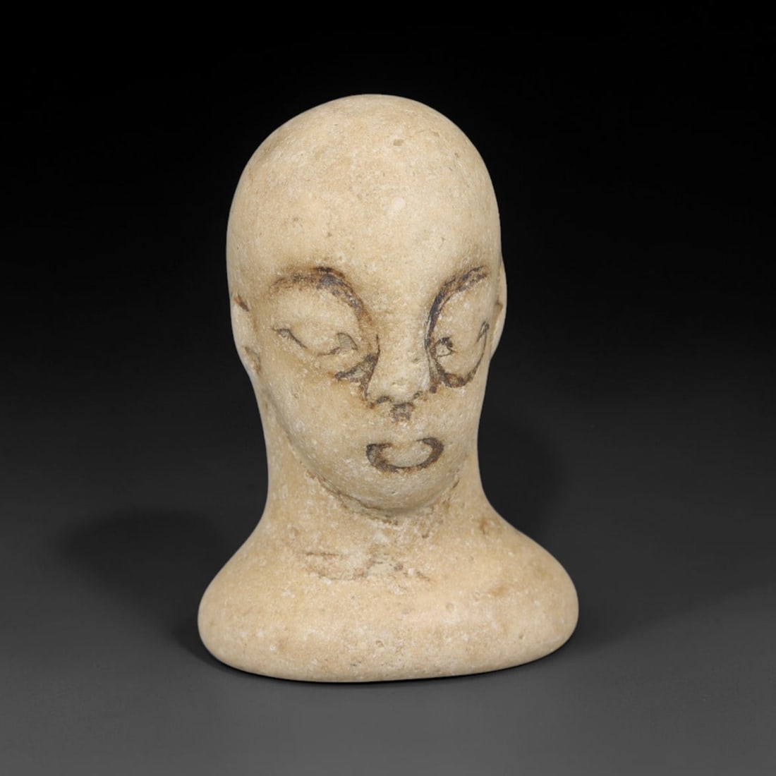 Ancient Bactrian Stone Head Effigy Amulet (c.2000-1500 BCE), 9EF: This pale stone miniature human head effigy originates from Ancient Bactrian culture. The stylised bust features incised facial detailing to define the eyes, nose and mouth, characteristic of Bactrian