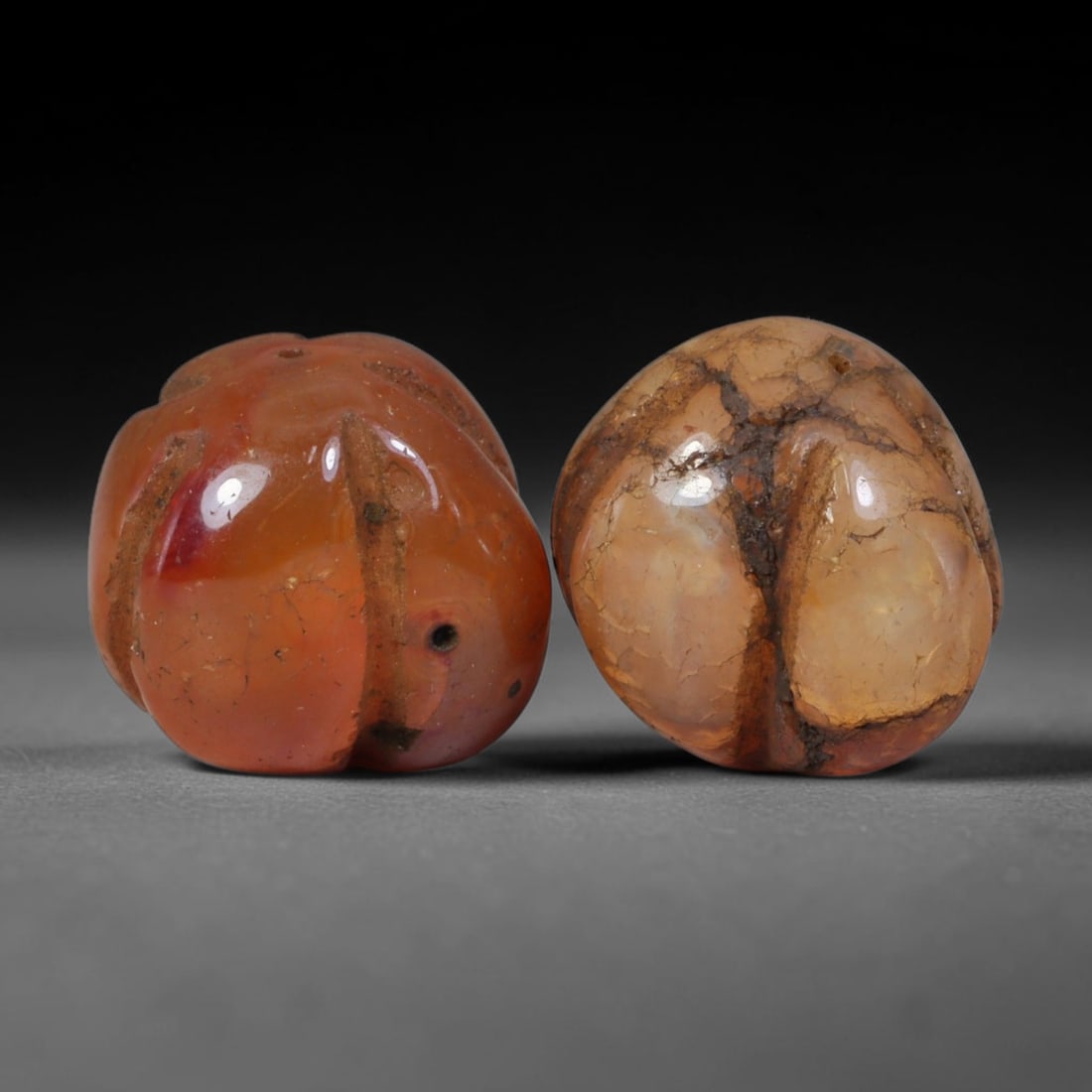 Ancient Medieval Khmer Angkor Culture Carved Carnelian Melon Bead Pair (802-1431 CE), 49AE: This matched pair of antique hand-carved melon form carnelian beads originates from Khmer Angkor Culture, the medieval Southeast Asian civilization renowned for crafting ritual chalcedony adornments f