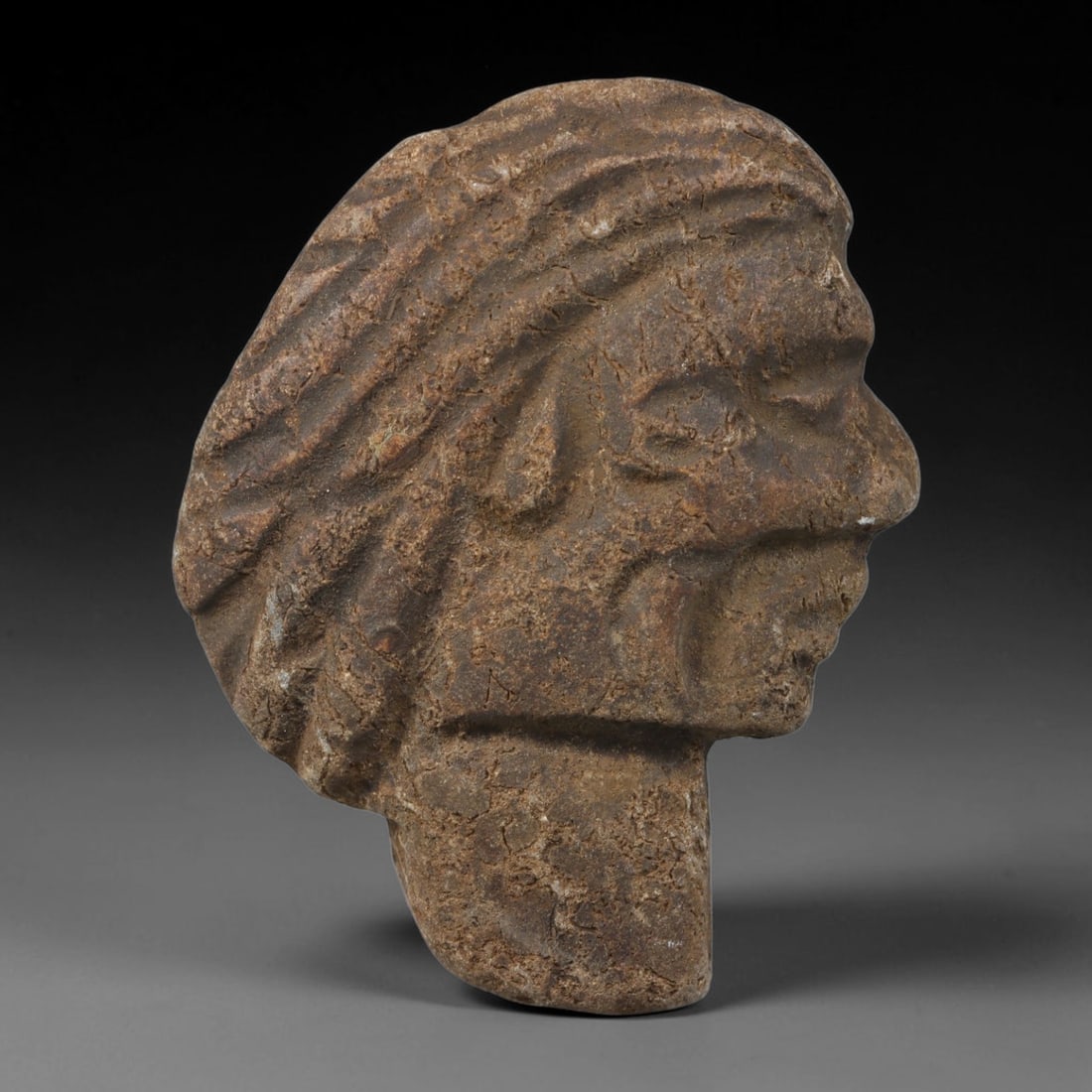 Ancient Medieval Near Eastern Tribal Hand Carved Stone Maskette Amulet, 37AC: Mid-sized antique wearable sacred talisman hand hewn from natural sedimentary stone, measuring 5cm x 4cm, originating from Medieval Near Eastern tribal cultural traditions. Hand-carved stone talismans