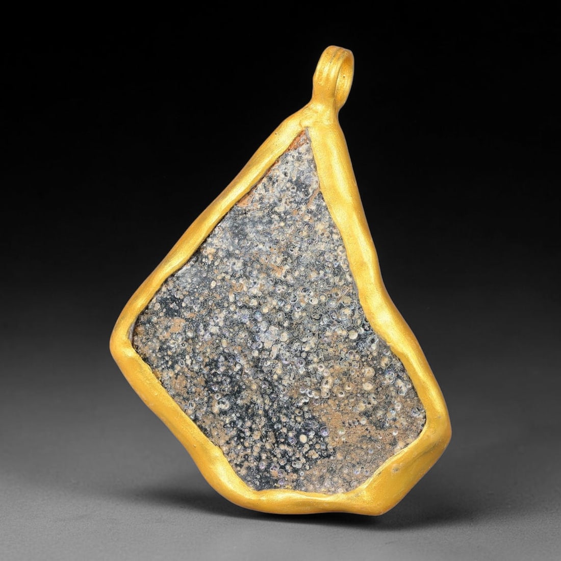 Ancient Roman Glass Slag in Modern Gilt-Edge Pendant, 49FY: This contemporary pendant is crafted from ancient Roman glass slag, featuring a fragmented, iridescent glass surface with weathered patina. The irregular form is bordered by a subtle gilt frame, added