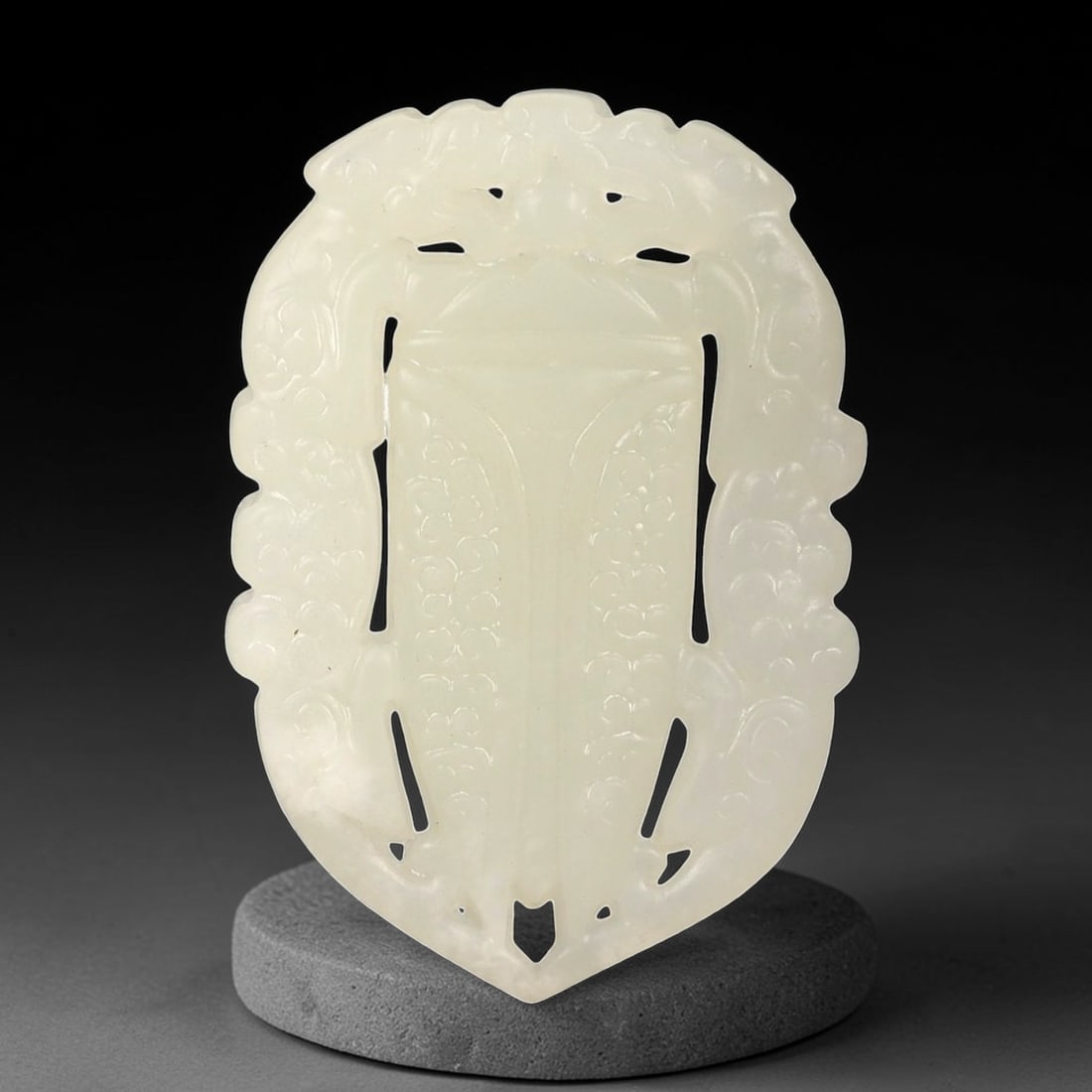 A Chinese Archaistic-Style Jade Openwork Plaque Pendant, 43FH: Carved from pale translucent jade with a milky white tone and subtle internal clouding, the plaque is formed as a vertically oriented openwork panel with a symmetrical outline tapering to a pointed lo