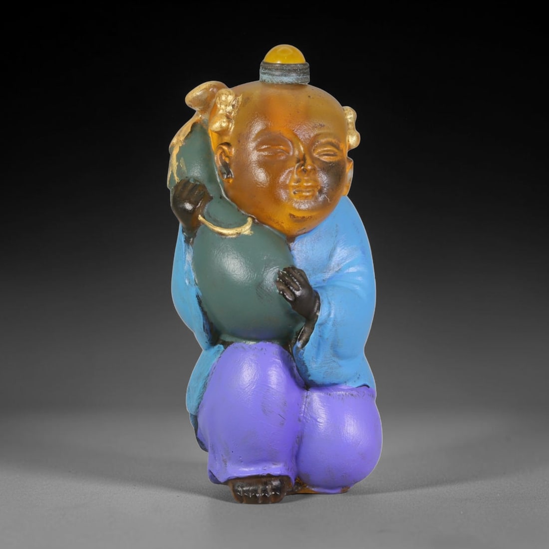 Vintage Chinese Liuli Glass Snuff Bottle - Boy Holding Gourd, 37AS: This snuff bottle is moulded from translucent amber liuli glass, shaped as a young boy cradling a green gilded gourd, a classic symbol of longevity and good fortune. His bright blue robe and purple tr