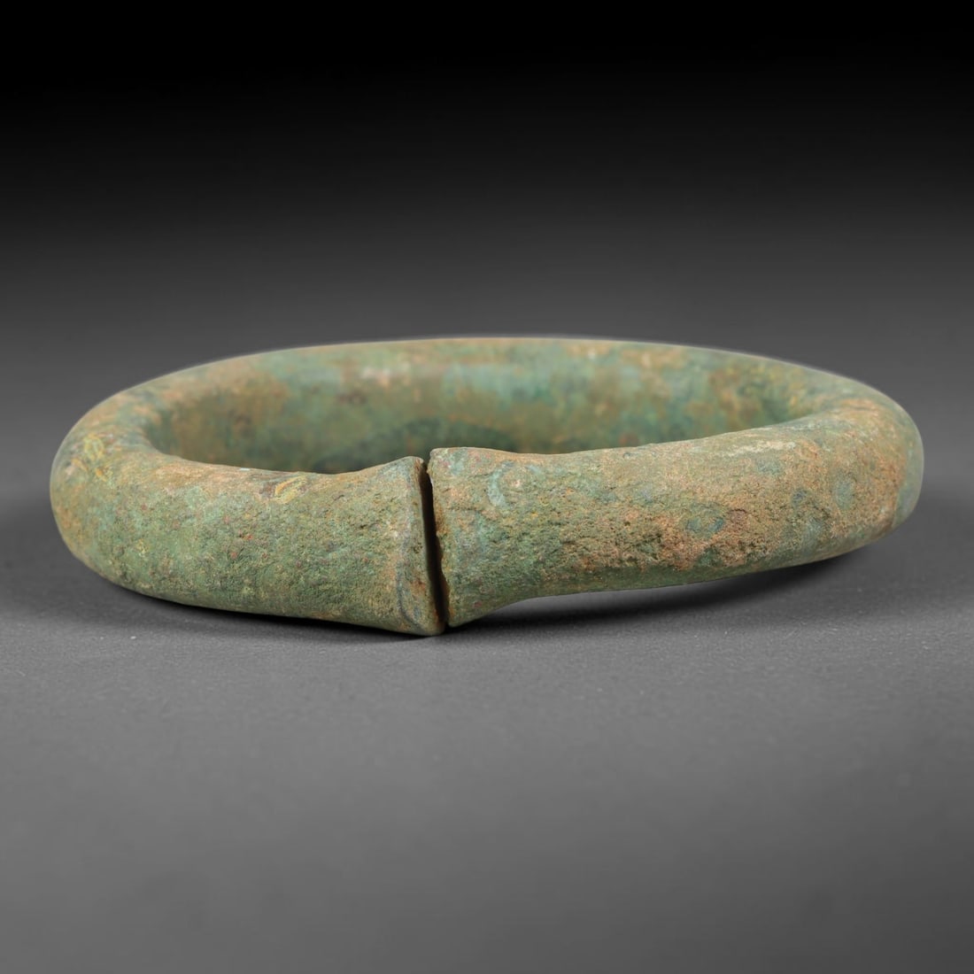 Ancient Roman Bronze Bangle Bracelet (100BCE-400 CE), 36EK: This antique bronze bangle bracelet originates from ancient Roman cultural tradition, created as wearable personal adornment. The metal displays thick, layered burial-formed patina across its surface,