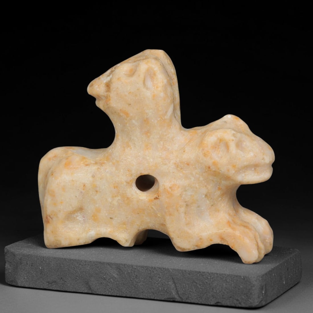 Ancient Sasanian Persian Double Zoomorphic Amulet (c.224-651 CE), 95ED: This pale mottled stone double zoomorphic amulet originates from Ancient Sasanian Persian culture. It features a unified recumbent body bearing two distinct animal heads, with a central suspension per