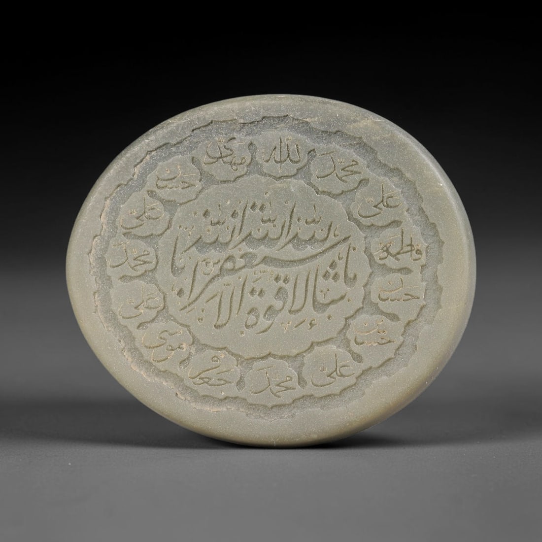 An Islamic Natural Green Stone Circular Script Engraved Talisman Tablet, 33FG: This polished green stone talisman tablet with elaborate concentric layered script engraving covering the central face, framed within a stylized petal-shaped inner border. Fine recessed engraved detai