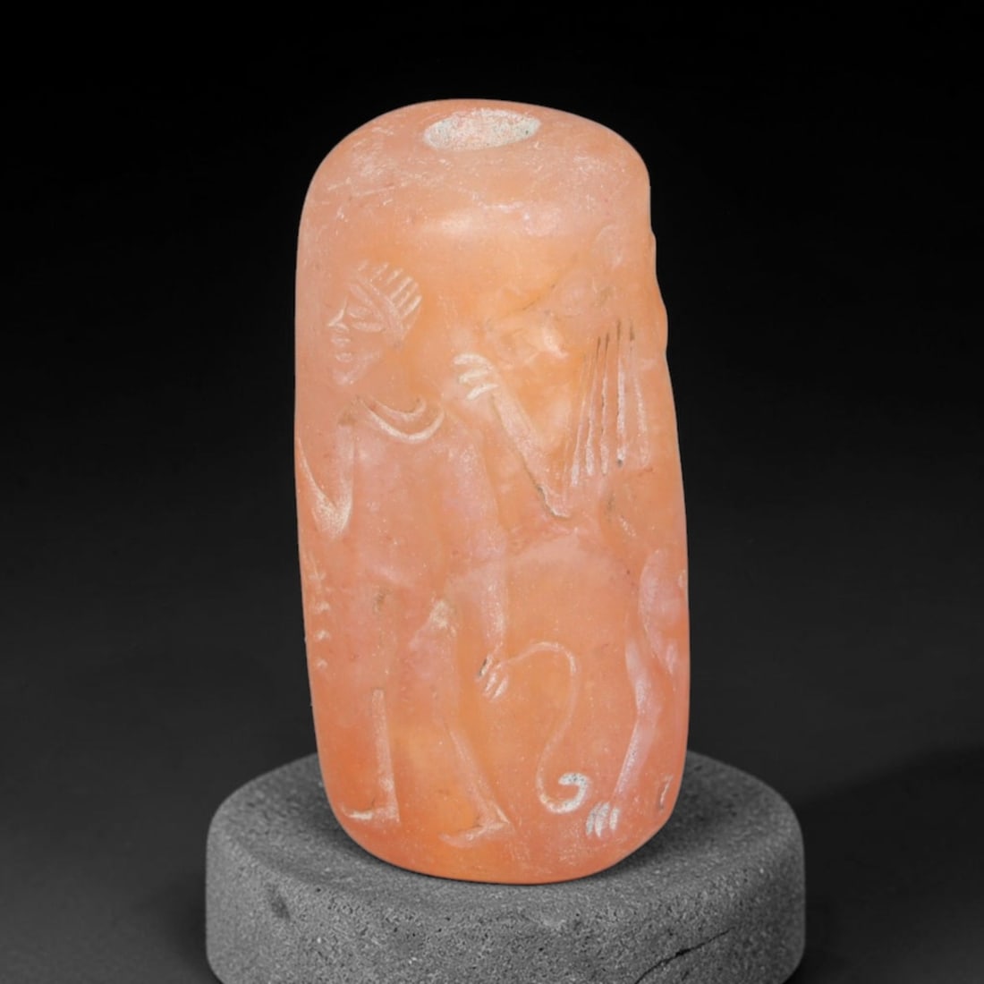 Ancient Achaemenid Persian Carnelian Cylinder Seal (550-330 BCE), 93EQ: This cylindrical seal is carved from warm translucent carnelian originating from the Achaemenid Persian cultural sphere, engraved with a scene featuring a standing human figure confronting a horned be