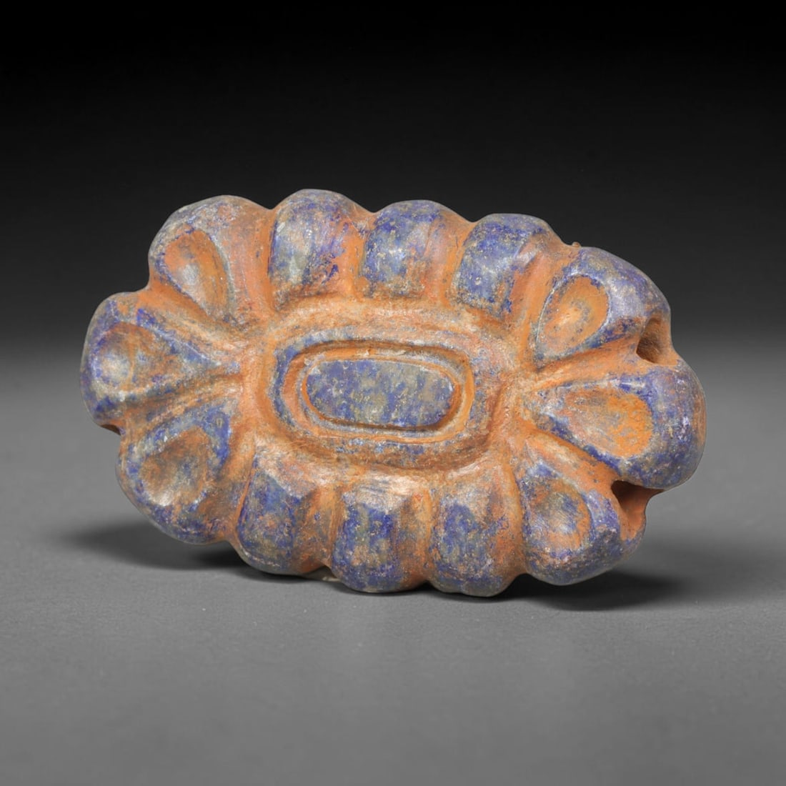 Ancient Achaemenid Persian Lapis Lazuli Rosette Bead (550-330 BCE), 1ER: This finely carved pendant bead is fashioned from rich lapis lazuli originating from the Achaemenid Persian Empire, decorated with a symmetrical rosette floral motif featuring incised leaf and lattice