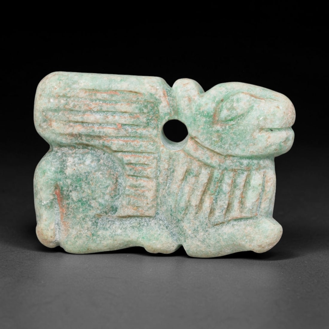 Ancient Bactrian Green Stone Winged Zoomorphic Ram Amulet (c.200-200 BCE), 78EQ: Carved from pale green mottled serpentine stone originating from ancient Bactria, Central Asia. This flat wearable amulet depicts a winged recumbent ram with crisp incised detailing defining wings and
