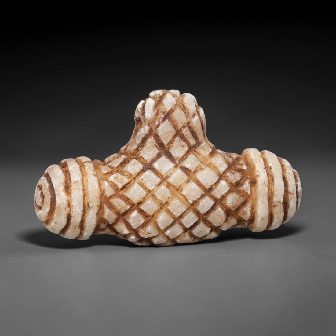 Ancient Medieval Seljuk Islamic White Stone Fertility Knot Talisman Amulet (c.1037-1194 CE), 67EQ: Carved from pale white calcite stone originating from the medieval Seljuk Islamic realm of Iran. This symmetrical wearable talisman is formed as a stylised fertility knot amulet, featuring deeply inci