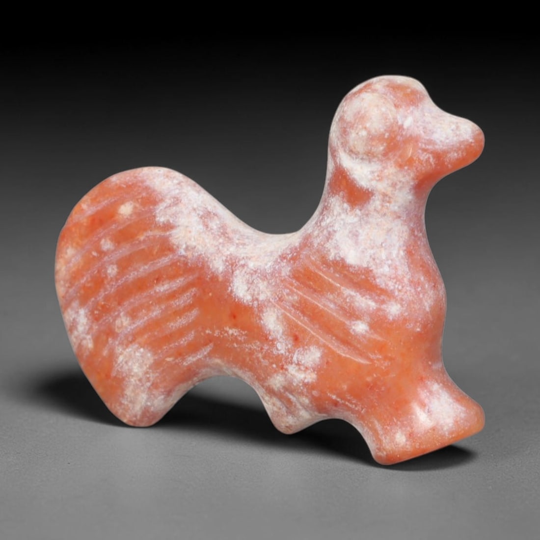 Ancient Bactrian Carnelian Cockerel Effigy Amulet (c.200-200 BCE), 89EQ: Hand-carved from warm orange-red carnelian originating from ancient Bactria, Central Asia. Crafted as a stylised standing cockerel talisman, this miniature wearable figure features incised linear deta