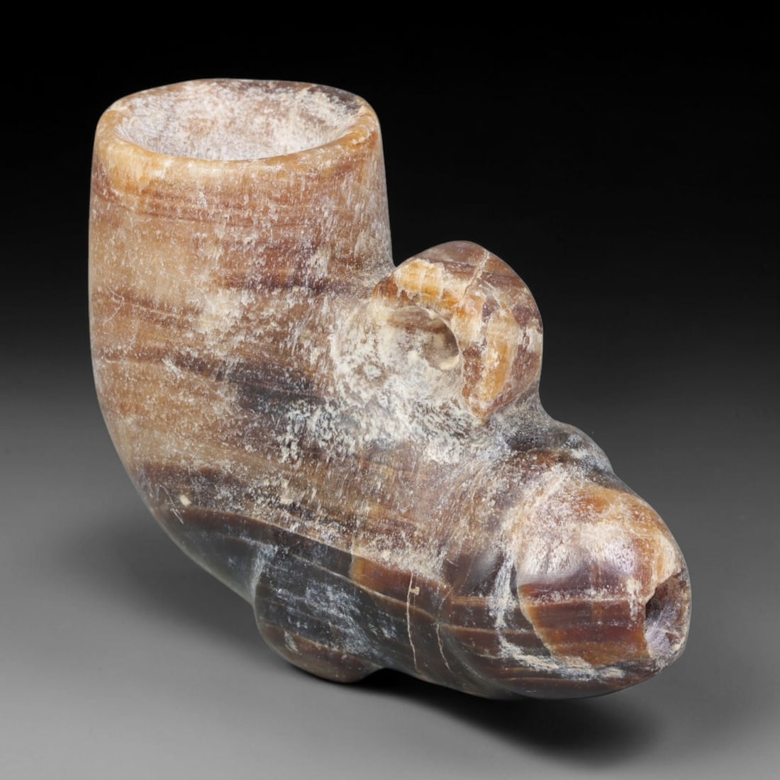 Ancient Medieval Seljuk Islamic Banded Calcite Phallic Libation Amulet Vessel (c.1037-1194 CE), 92EQ: Carved from naturally layered banded calcite, this miniature wearable ritual vessel originates from the Seljuk Islamic period of medieval Iran. Modelled as a stylised phallic form, the object function