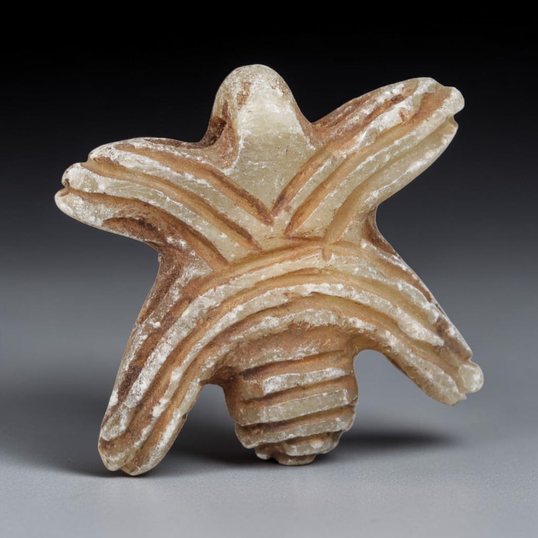 Ancient Bactrian Calcite Starform Insect Amulet (c.200-200 BCE), 97EQ: Hand-carved from pale translucent calcite originating within ancient Bactria, Central Asia. Crafted as a five-pointed star-shaped insect talisman with deeply incised linear grooves detailing segmented
