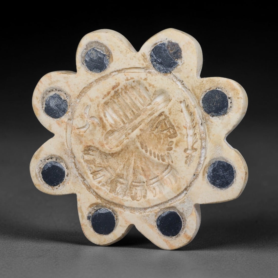 Ancient Neo-Hittite Floral Form Inlaid Limestone Stamp Seal (1200-800 BCE), 16EF: This eight-petalled floral stamp seal is carved from pale limestone, originating from Iron Age Neo-Hittite cultures of Northern Syria and Eastern Anatolia. Each petal is set with dark circular stone i