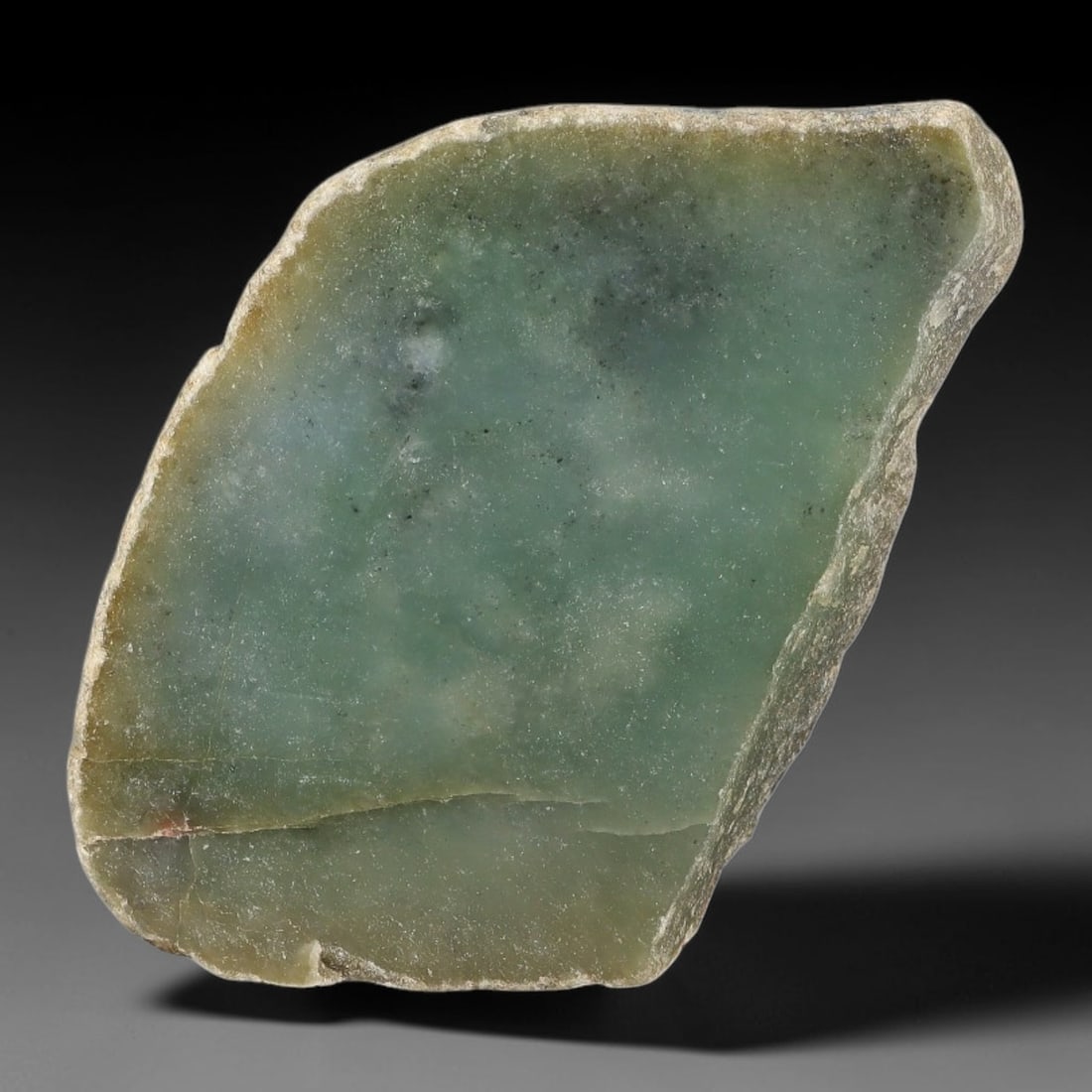 270ct Natural Type A Burmese Muted Teal Speckled Jadeite Jade Sliced Rough, 8FA: This specimen is a natural sliced rough slab of untreated Type A Burmese jadeite, retaining thin weathered pale tan outer rind around its irregular edge perimeter. Its polished interior face features 