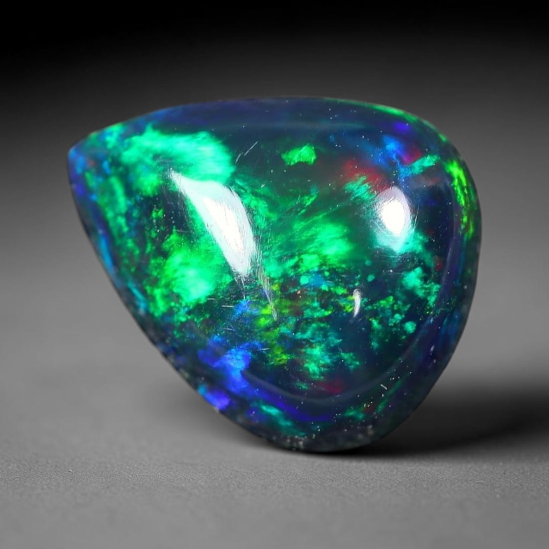 2.33ct Natural Ethiopian Welo Black Smoked Opal Cabochon Loose Gemstone, 65FX: This fully polished Ethiopian Welo opal features a dark smoked base with vivid, sweeping play-of-color shifting across its glossy dome surface, measured at 10x8x5mm. The black smoke treatment deepens 