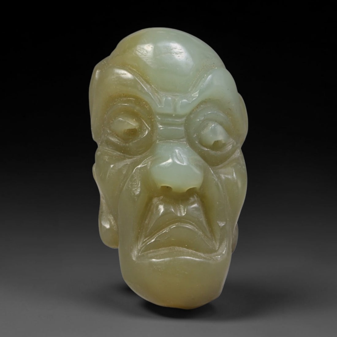 Natural Vintage Chinese Nephrite Jade Pale Celadon Wide-Eyed Arhat Head Carved Face Bead, 36AP: Hand-carved vintage Chinese strung bead crafted from natural vintage Chinese nephrite jade, measuring 3cm x 1.8cm. This barrel-form bead is sculpted into a striking wide-eyed Buddhist Arhat facial bus