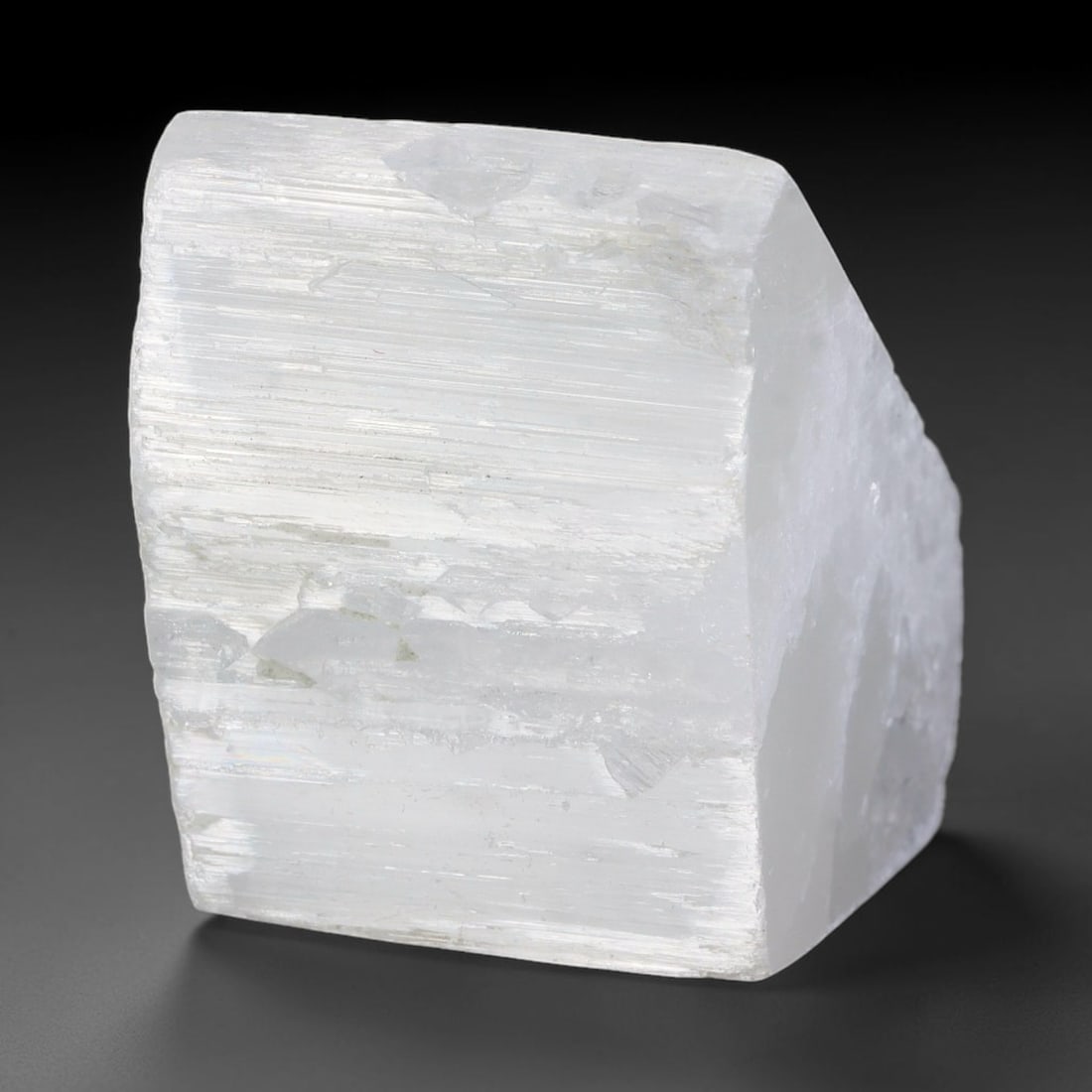 121ct Natural Moroccan Transparent White Selenite Rough Block, 89AH: This solid selenite rough block features milky translucent white body marked by distinct parallel internal striations that catch soft diffused light across its naturally faceted raw planes, faint pale